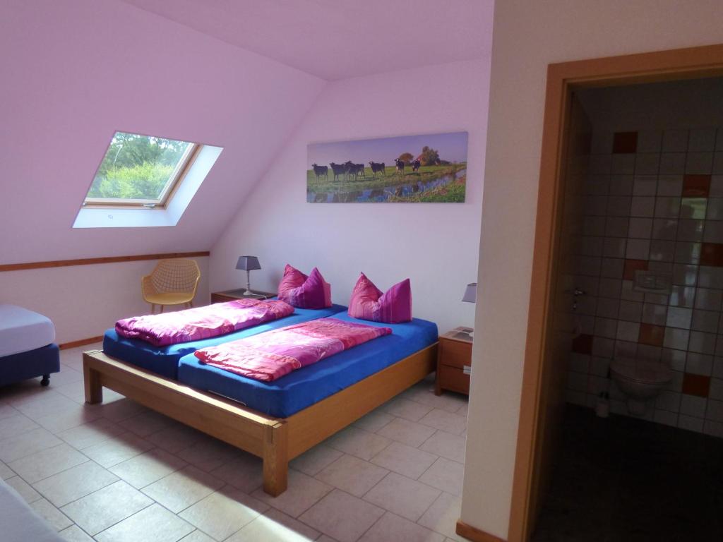 a bedroom with a blue bed with pink pillows at Heidehof Pension B & B in Elten