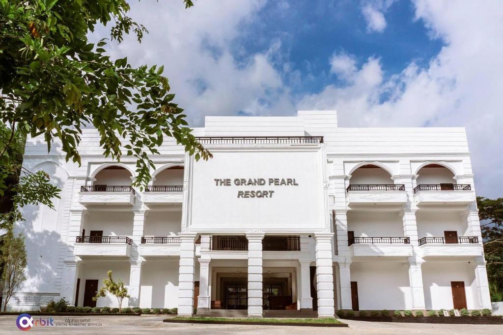 a white building with a sign that reads we grand palm resort at The Grand Pearl Resort in Monaragala