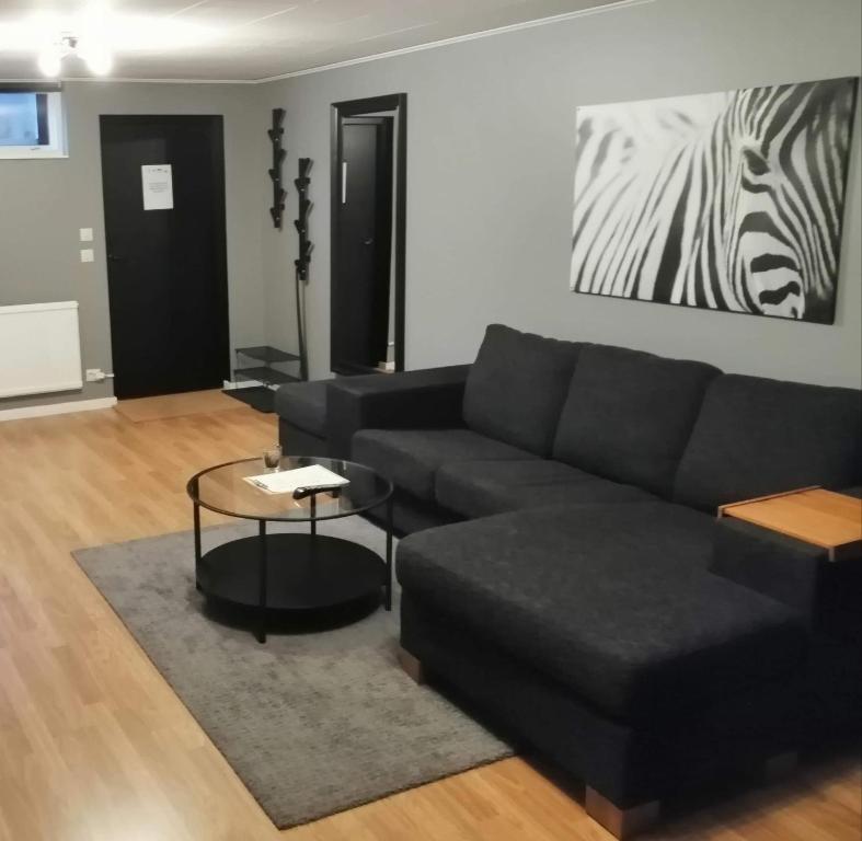 ein Wohnzimmer mit einer schwarzen Couch und einem Zebra-Gemälde in der Unterkunft 4Stay Vislanda Apartment in Vislanda