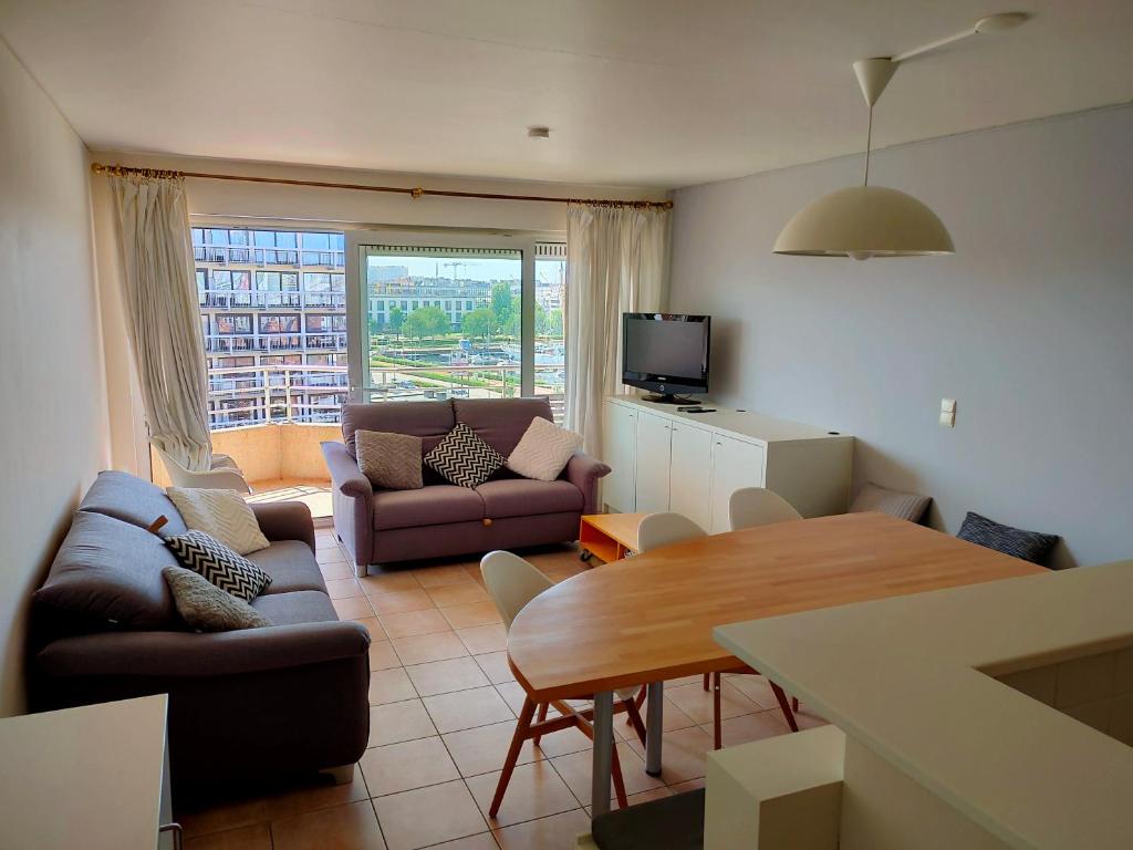 un soggiorno con divano e tavolo da pranzo di Zongericht appartement met zicht op de jachthaven a Ostenda