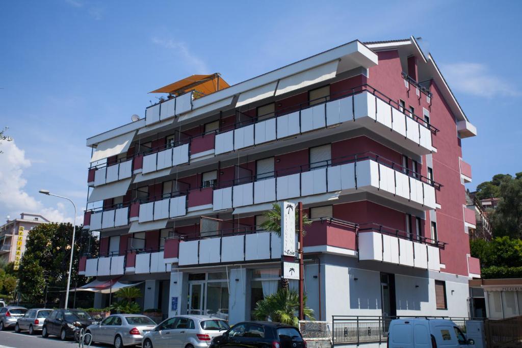 un edificio rojo con coches estacionados frente a él en Residence La Palma, en Andora