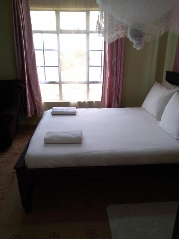 a bed with two towels on it in a room with a window at Crown Hotel Kericho in Kericho