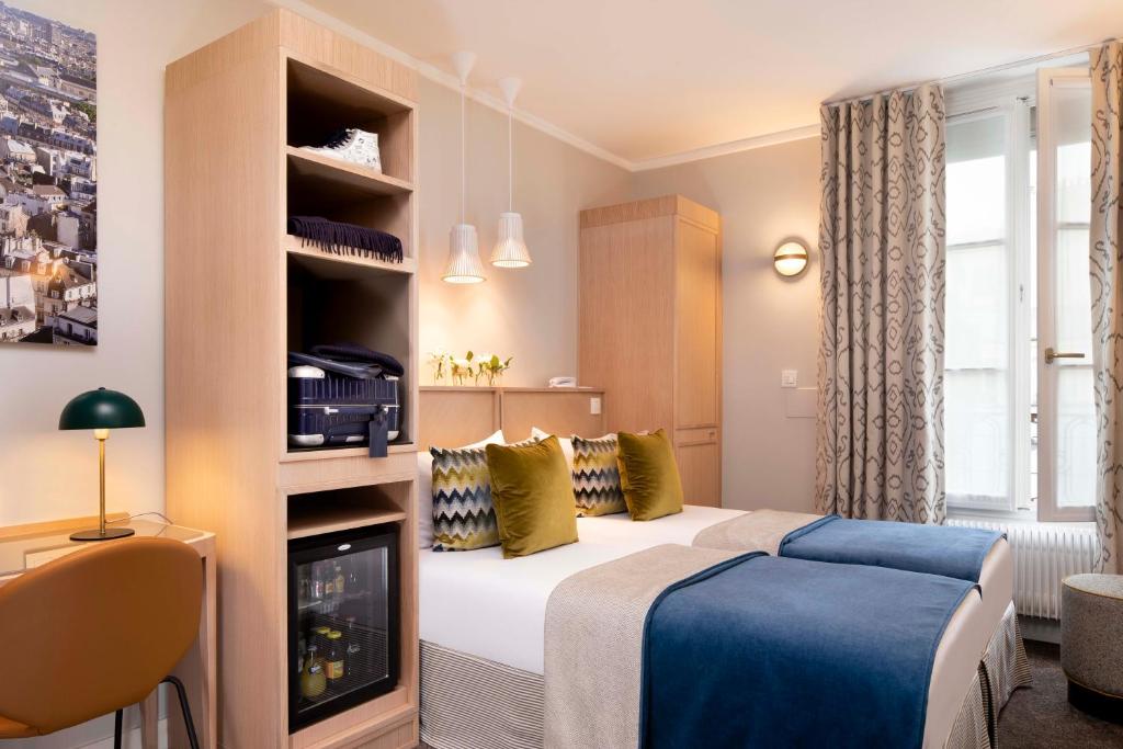 a bedroom with a bed, desk and a television at Jardins Eiffel in Paris