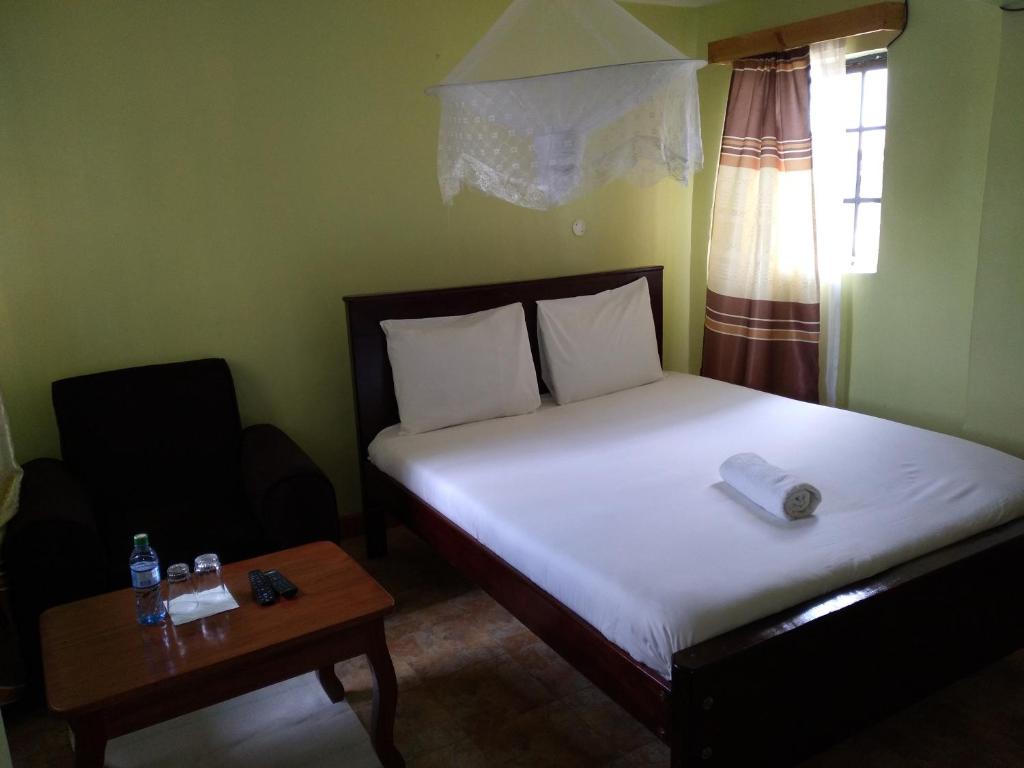 a small bedroom with a bed and a table at Crown Hotel Kericho in Kericho