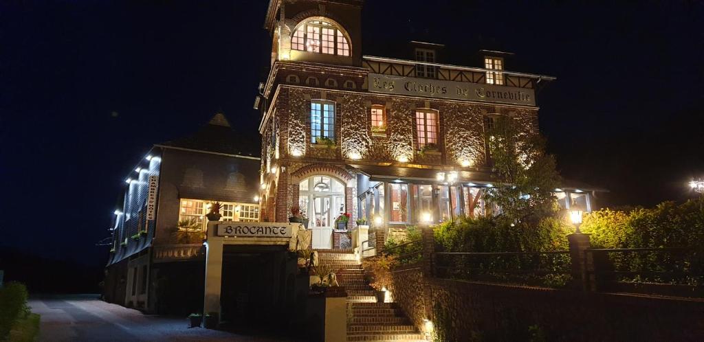 a lit up building with a clock tower at night at Les Cloches de Corneville in Corneville-sur-Risle