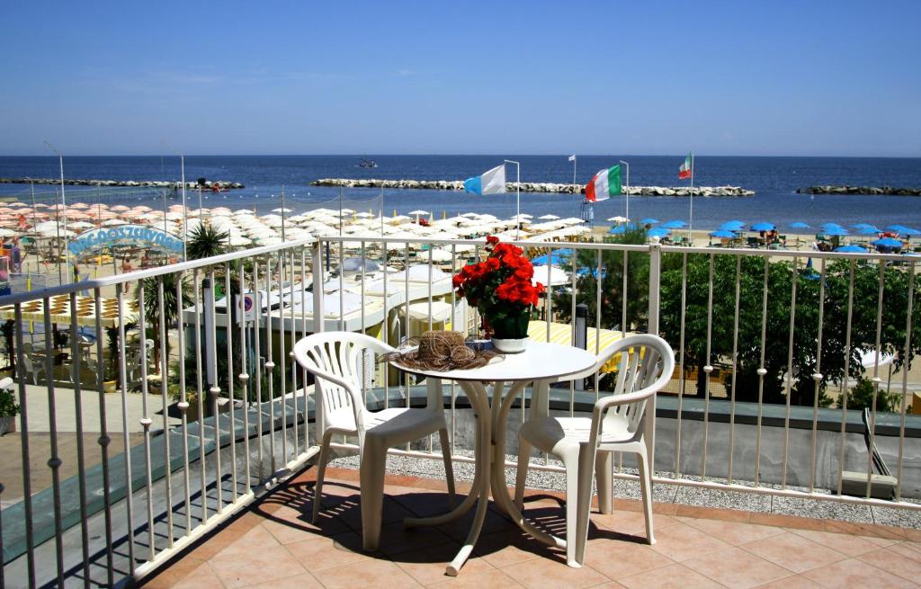 einen Tisch und Stühle auf einem Balkon mit Blick auf den Strand in der Unterkunft Hotel Excelsior in Bellaria-Igea Marina