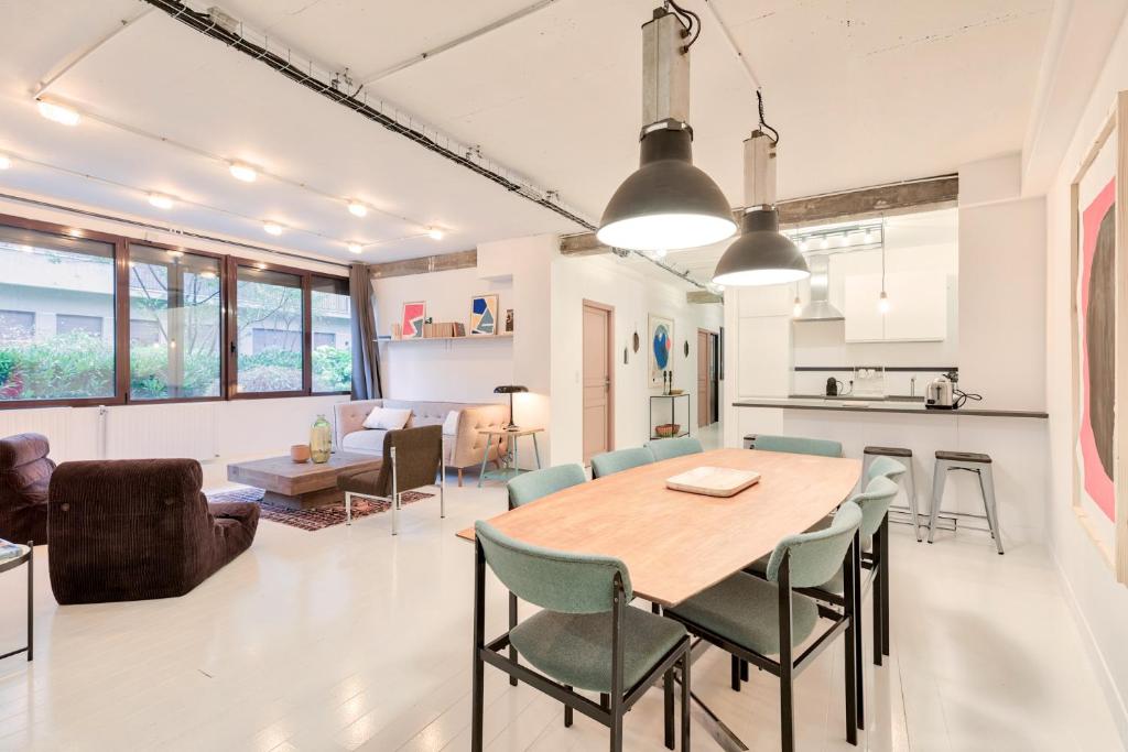 eine Küche und ein Wohnzimmer mit einem Holztisch und Stühlen in der Unterkunft Artist and Design Loft - 10 Guests - 5 Min From Metro in Paris