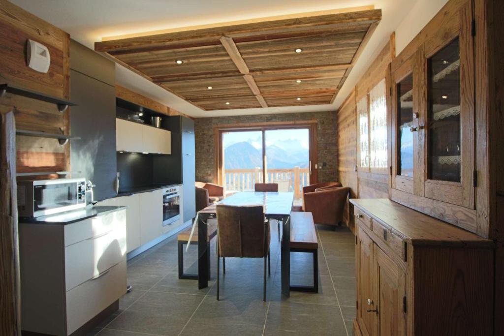 une cuisine et une salle à manger avec une table et des chaises dans l'établissement ODYSSEE B203 Vaste appartement en vieux bois sur les pistes, vue panoramique, à La Toussuire