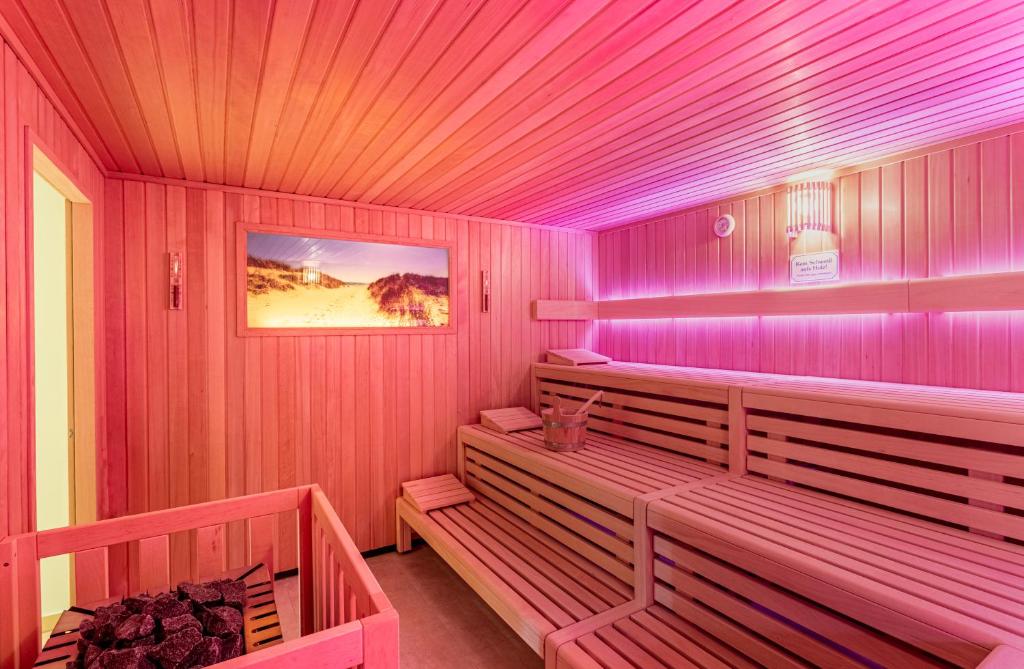 um quarto rosa com bancos numa sauna em Ringhotel Warnemünder Hof em Warnemünde