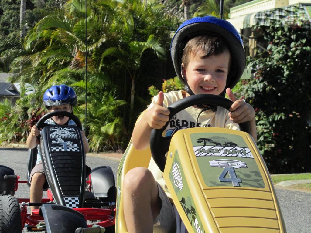 a young boy is riding on a toy car at NRMA Capricorn Yeppoon Holiday Park in Yeppoon