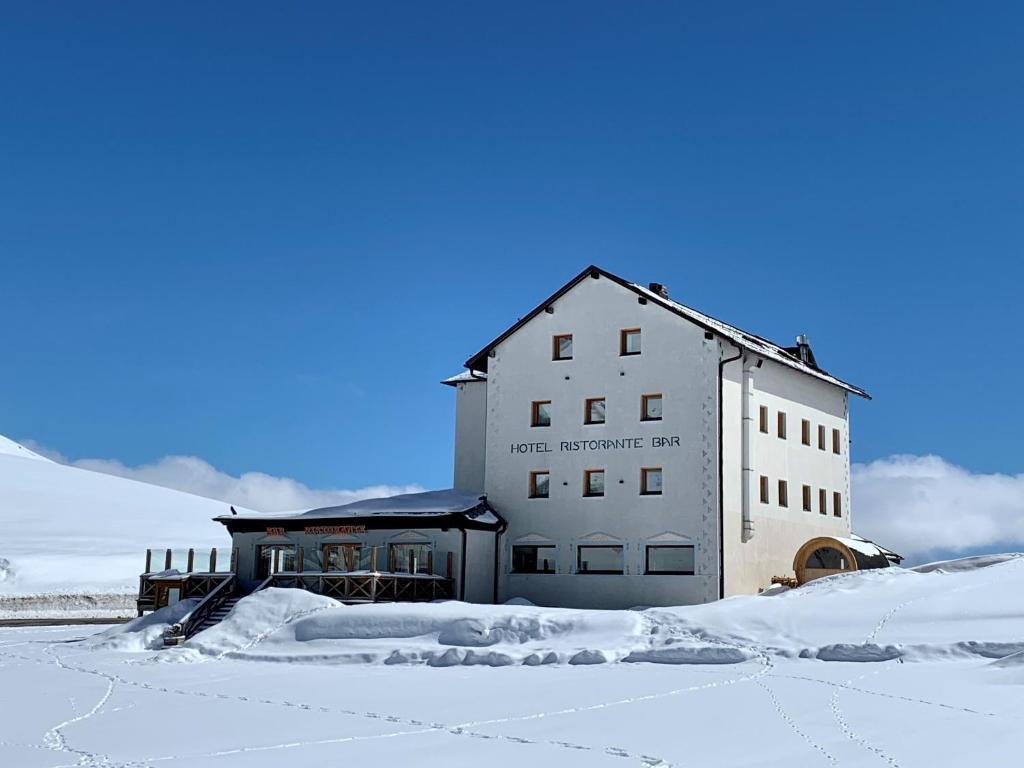 a white building in the snow with snow covered ground at Hotel Col di Lana in Canazei