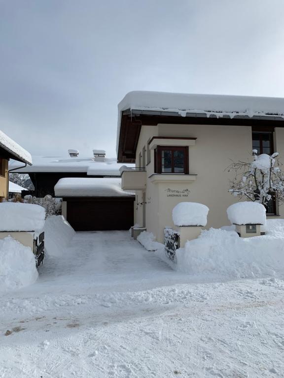 a house covered in snow with benches in front of it at Landhaus MAX in Garmisch-Partenkirchen
