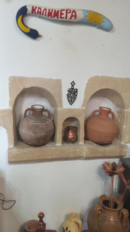 a shelf with several clay pots on a wall at TRADITIONAL HOUSE MARIA in Azoyirás