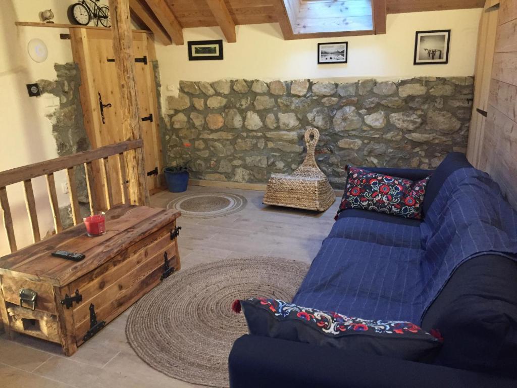 sala de estar con sofá azul y pared de piedra en La Lauze village house in Clarée Valley 4P, en Val-des-Prés