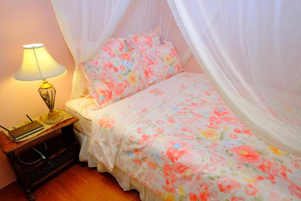 a bedroom with a bed with a canopy and a lamp at Spring Garden Homestay in Hualien City