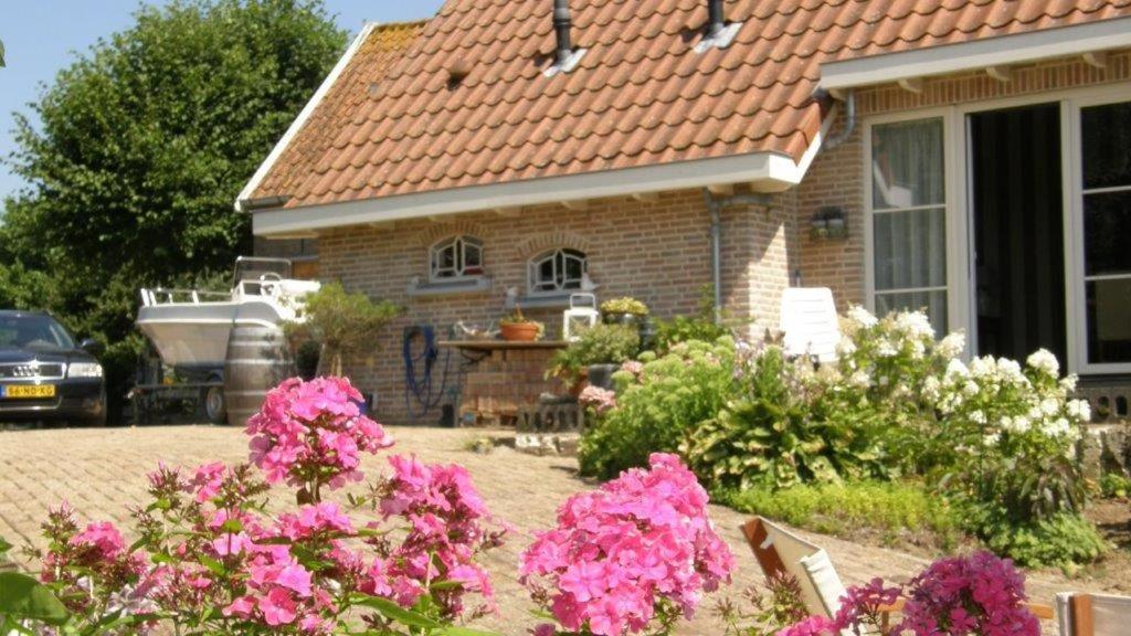 a house with pink flowers in the front yard at B&B de Oude Hofstee in Maasdam