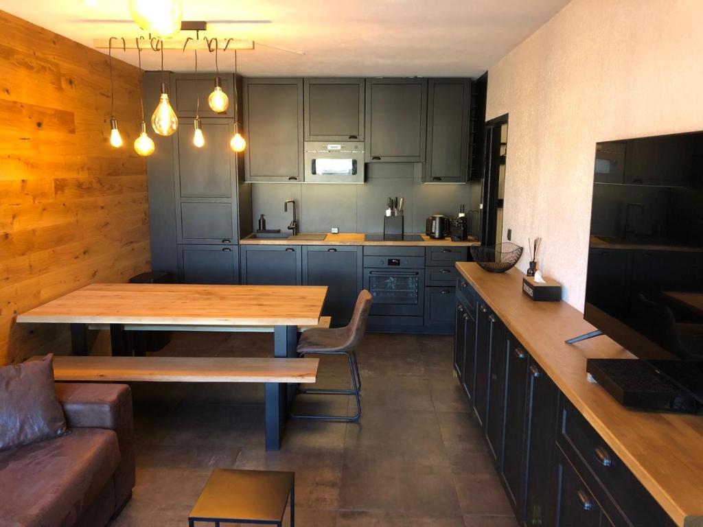 una cucina con tavolo in legno e divano di Magnifique appartement pied des pistes a Métabief