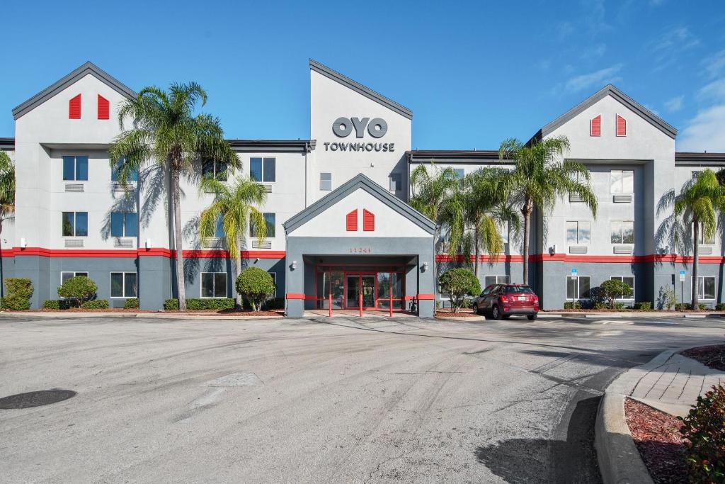 um grande edifício branco com palmeiras em frente em OYO Townhouse Orlando West em Orlando
