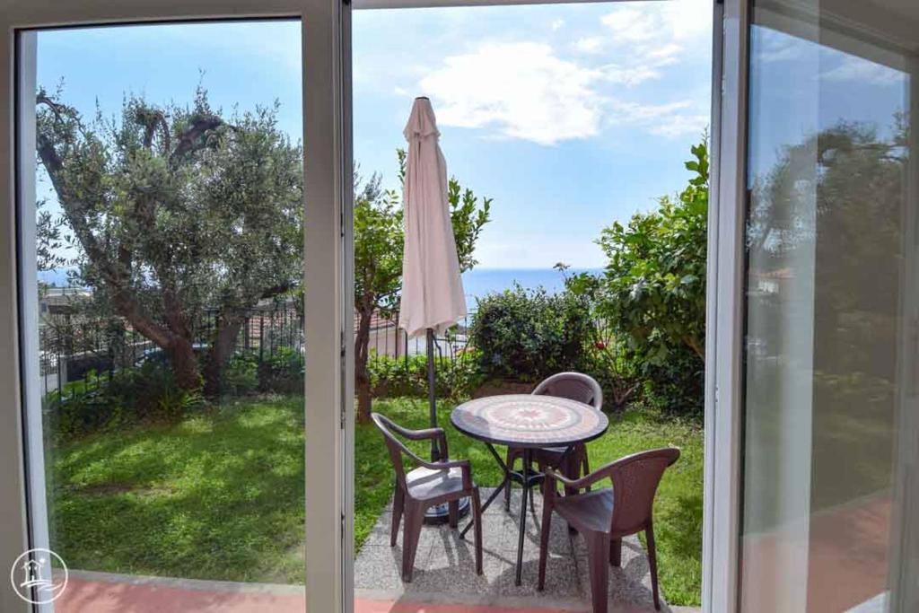 un patio avec une table, des chaises et un parasol dans l'établissement Casa Vacanze Casa Barbara, à Finale Ligure