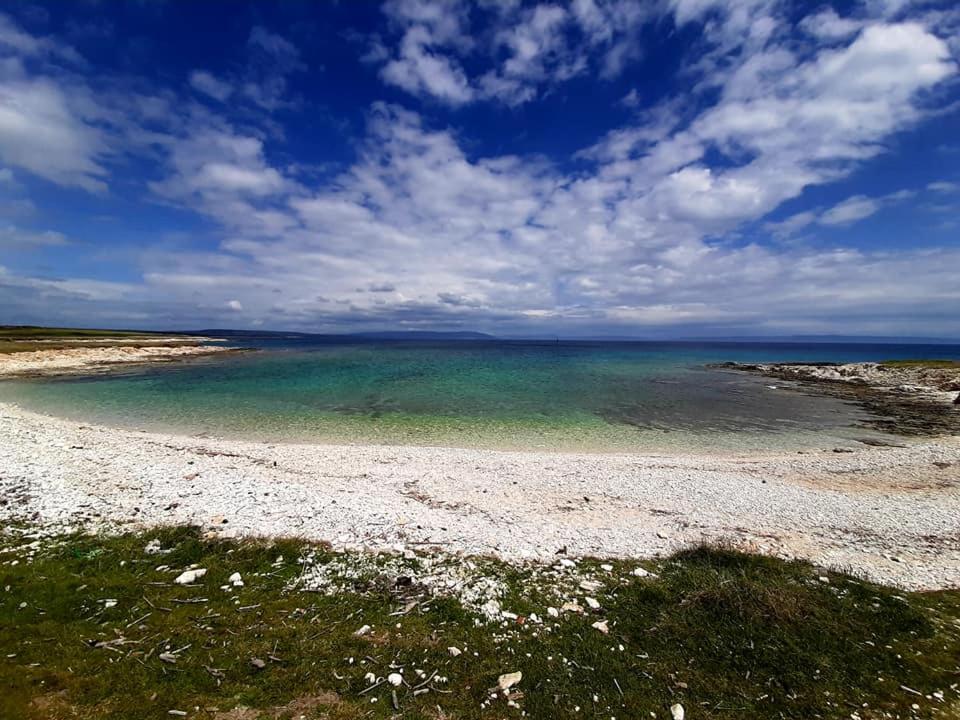 a beach with a blue sky and the water at Holiday Home Aurora in Ližnjan