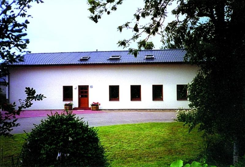 a large white building with red doors and a yard at Ferienhof Budach in Handewitt