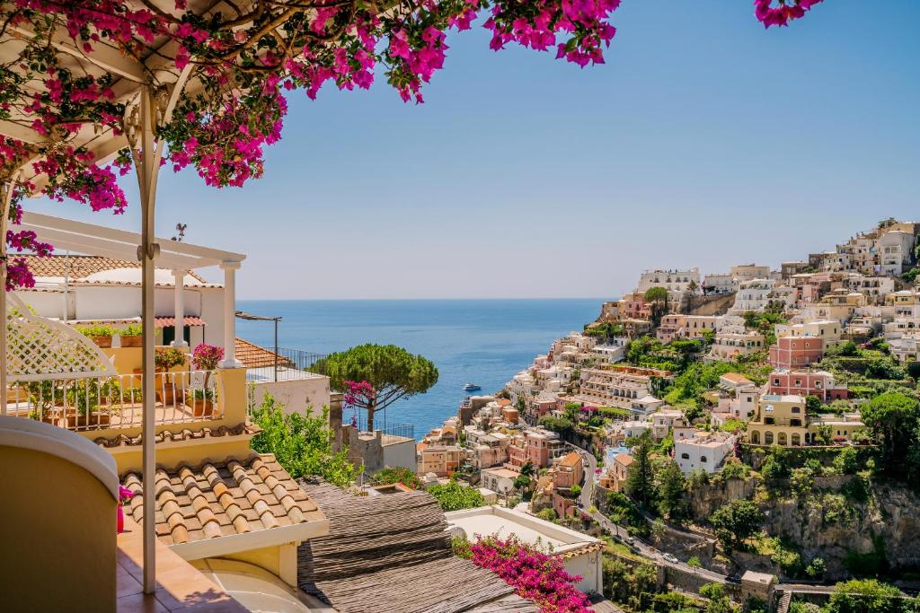 uma vista para o positano a partir de uma colina com flores cor-de-rosa em Villa Mary Suites em Positano