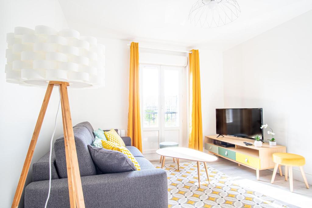 un salon avec un canapé bleu et une télévision dans l'établissement Danton Renaissance - F2 rénové - Tout équipé, au Havre