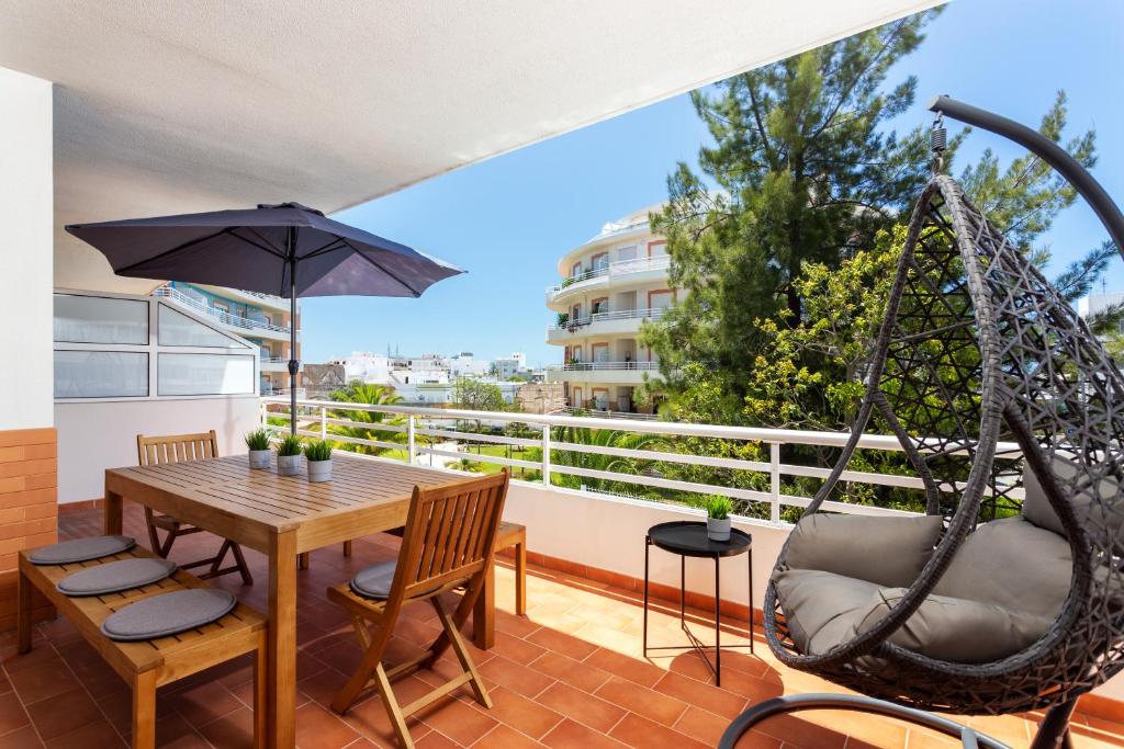 eine Terrasse mit einer Hängematte sowie einem Tisch und Stühlen in der Unterkunft Privilege Apartment Magnolia, Olhão in Olhão