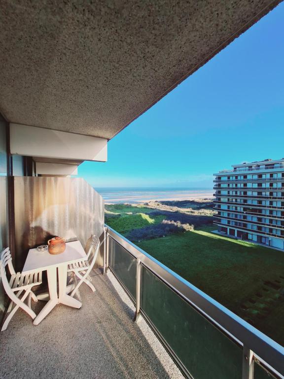 a balcony with a table and chairs and a view of the ocean at Klif studio 612 La Panne in De Panne