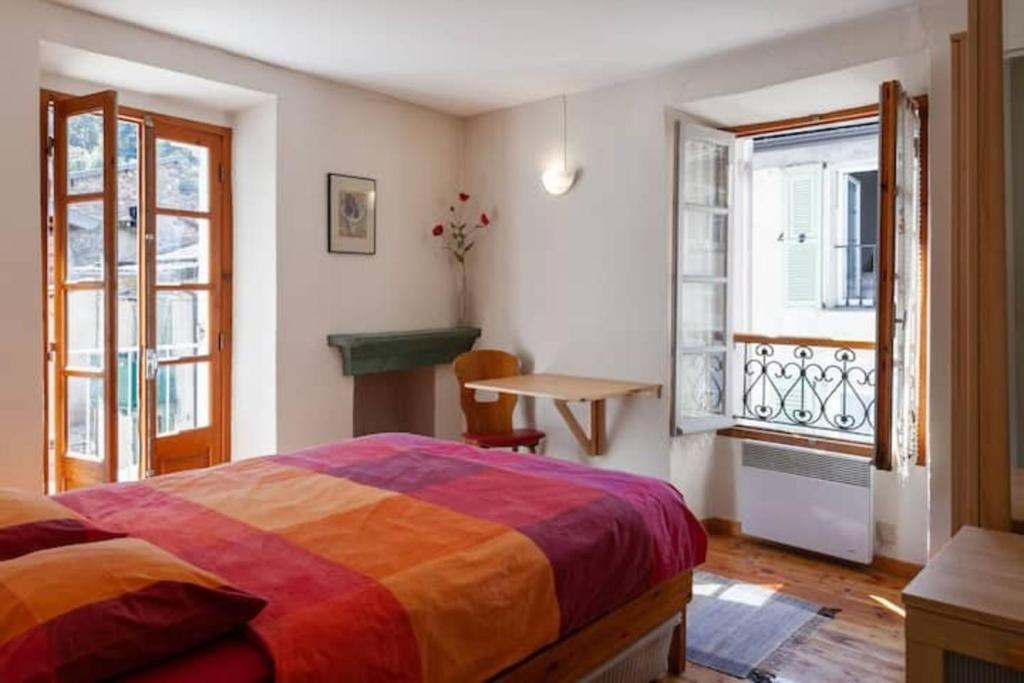 a bedroom with a bed and a window and a table at Sunny 1-Bed apartment in lovely mountain village in La Brigue