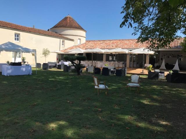 um quintal com cadeiras e mesas e um edifício em Le Logis du Péré em Saint-Coutant-le-Grand