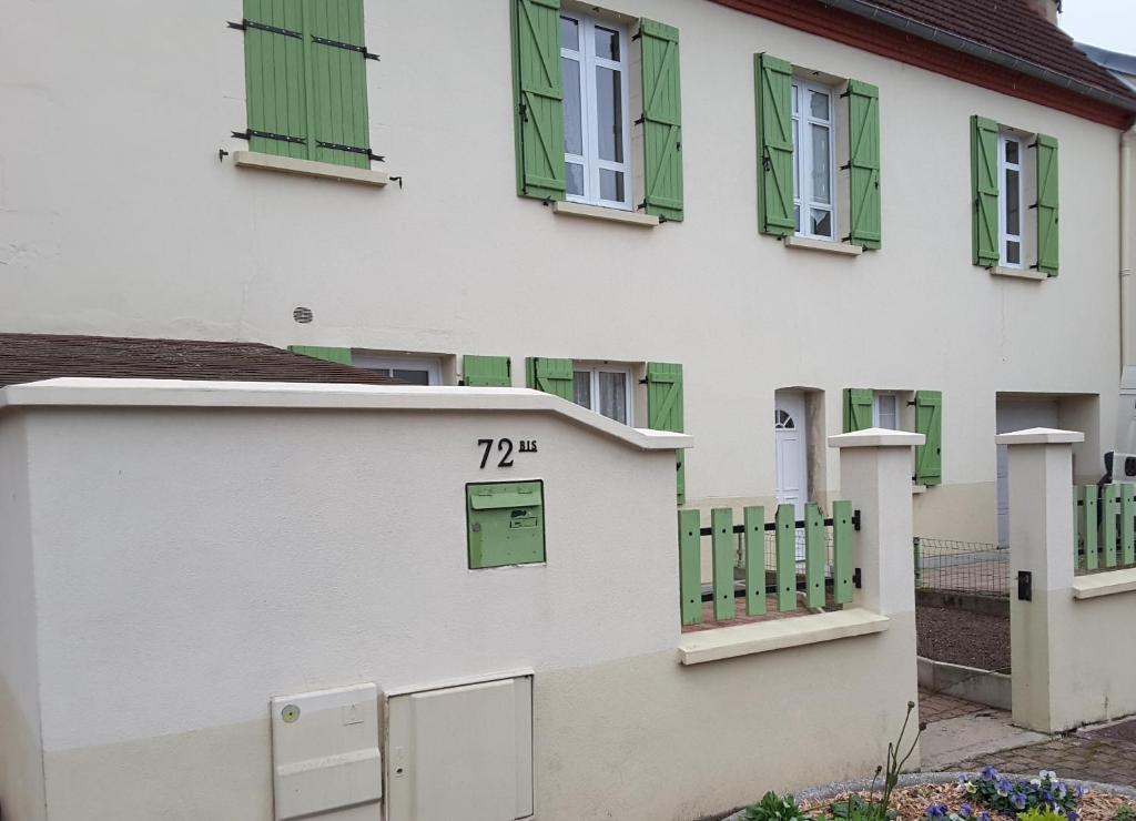 uma casa branca com janelas verdes e um número nela em Chez Christian em Désertines