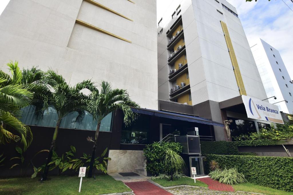 um edifício com palmeiras em frente em Rede Andrade Vela Branca em Recife