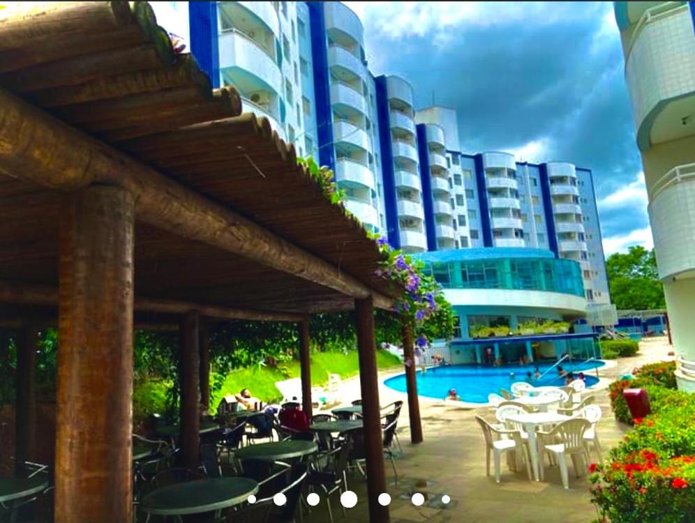 a building with tables and chairs and a swimming pool at Águas da Serra in Rio Quente