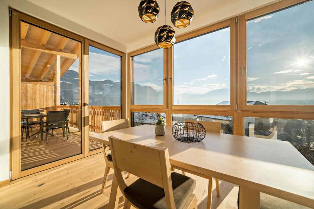 - une salle à manger avec une table, des chaises et de grandes fenêtres dans l'établissement Apt Eiche - Nockerhof, à Andrian