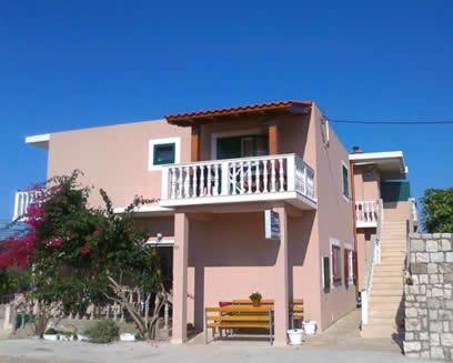 un bâtiment rose avec un balcon et un banc dans l'établissement Studio Manora Sucuraj, à Sućuraj