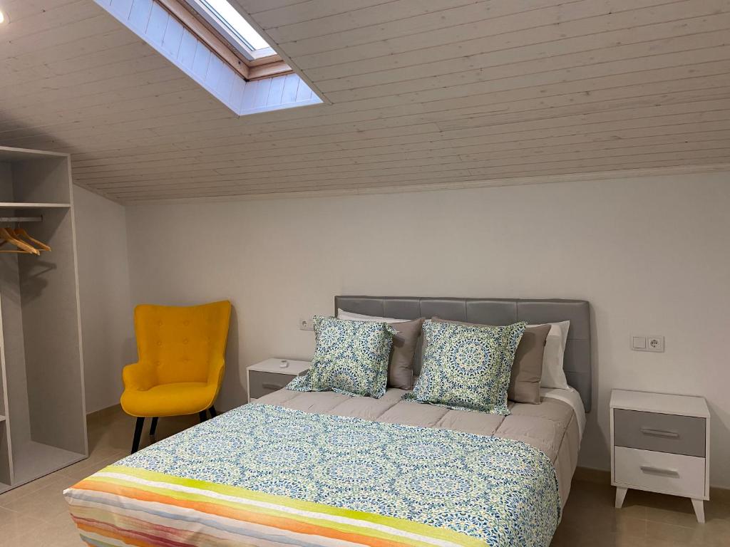 ein Schlafzimmer mit einem Bett und einem gelben Stuhl in der Unterkunft Os Arcos - Apartamentos Turísticos in Portomarin