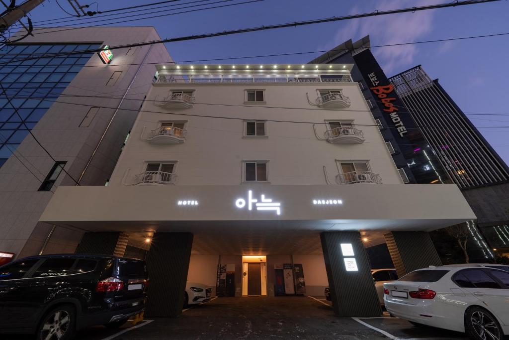 テジョンにあるAank Hotel Daejeon Yongjeon 1の車が目の前に停まった白い建物