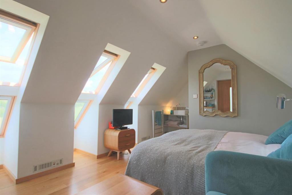 a attic bedroom with a bed and a mirror at Pudswell Studio in Burford