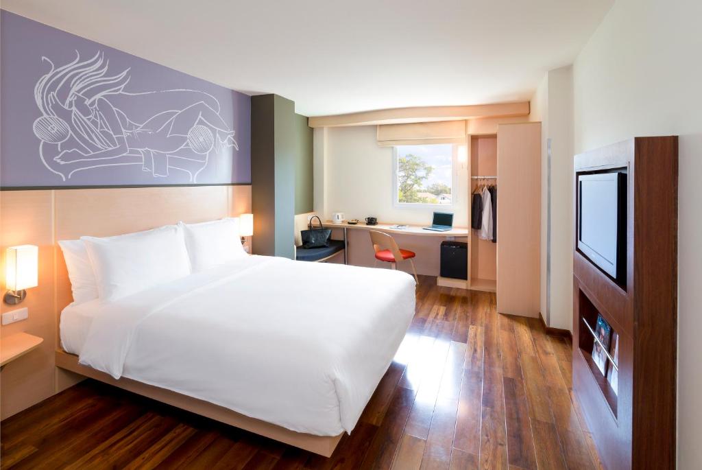 a bedroom with a large white bed and a desk at ibis Vientiane Nam Phu in Vientiane