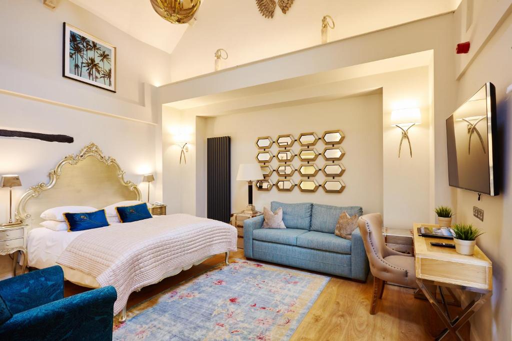 a bedroom with a bed and a blue couch at The Ormond At Tetbury in Tetbury