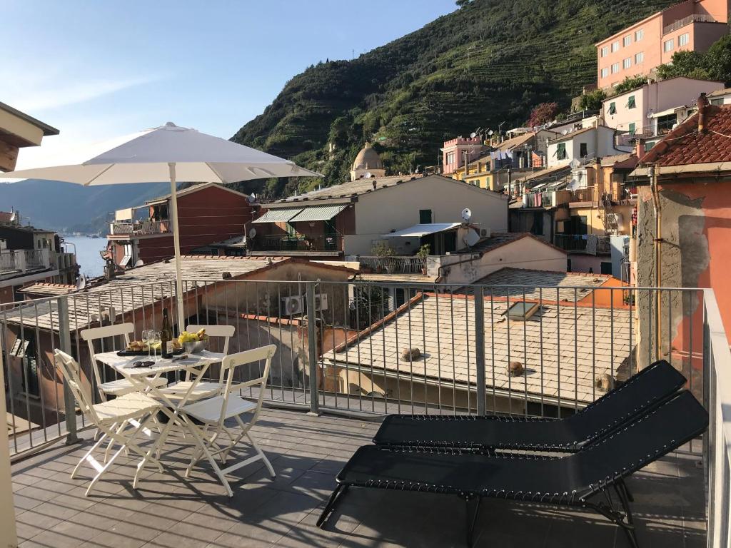 a balcony with a table and chairs and an umbrella at Carattino in Vernazza