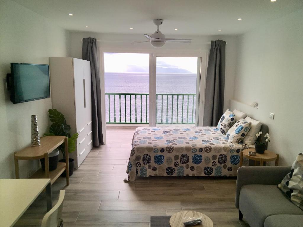 a bedroom with a bed and a view of the ocean at Look and listen to the ocean like never before in Puerto de Santiago
