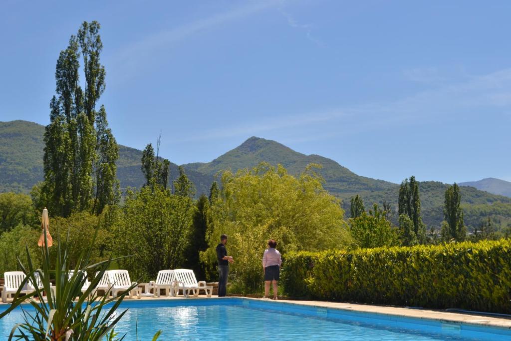 two people standing by a swimming pool with mountains in the background at Auberge Les Sibourgs in Bourdeaux