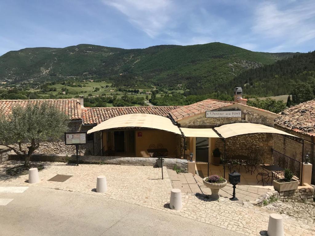 ein Gebäude mit zwei Sonnenschirmen davor in der Unterkunft Hotel L'Oustau de la Font in Reilhanette