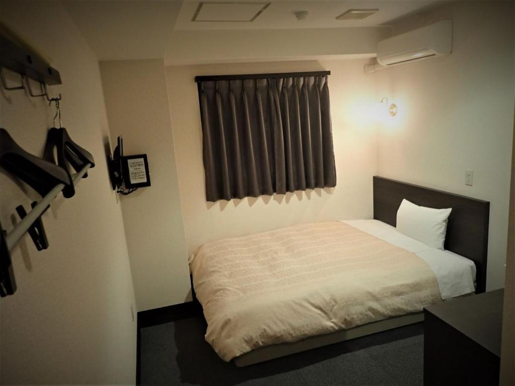 Un dormitorio pequeño con una cama con ventana. en Hotel Suntargas Ueno - Vacation STAY 08484v, en Tokio