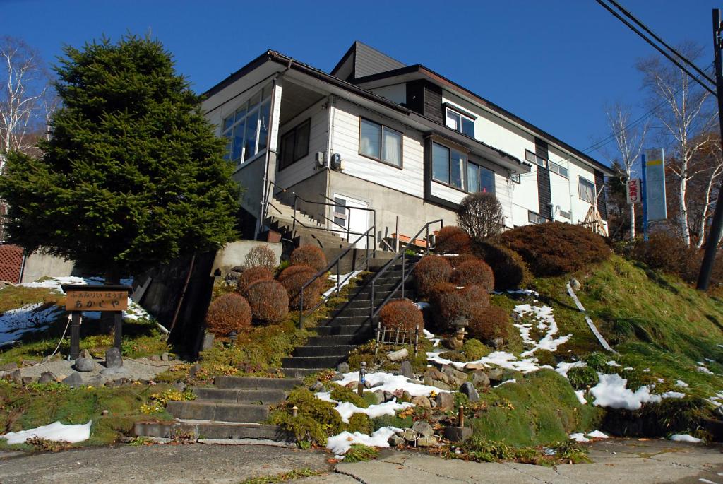 a house on a hill with snow on the stairs at Family House Akashiya in Yuzawa