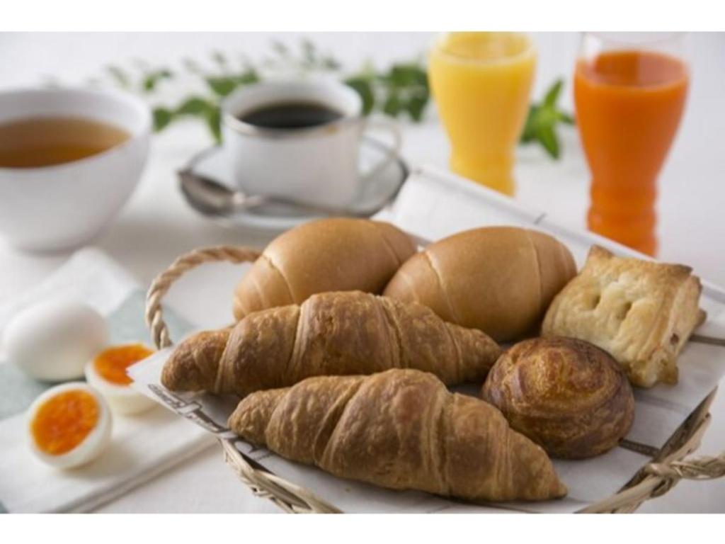 un piatto di pane e cornetti e una tazza di caffè di R&B Hotel Shin Yokohama Ekimae - Vacation STAY 14695v a Yokohama