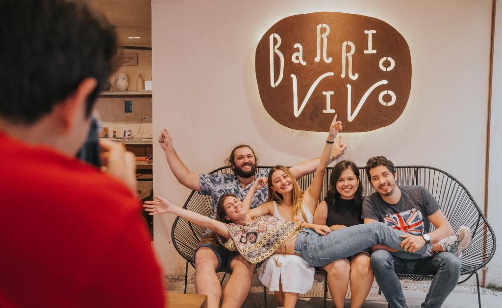 a group of people sitting on a bench with their hands in the air at Hostal Barrio Vivo in Mérida