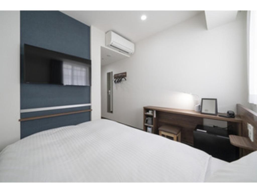 a bedroom with a white bed and a desk and a bed sidx sidx sidx at R&B Hotel Nagoya Ekimae - Vacation STAY 15184v in Nagoya